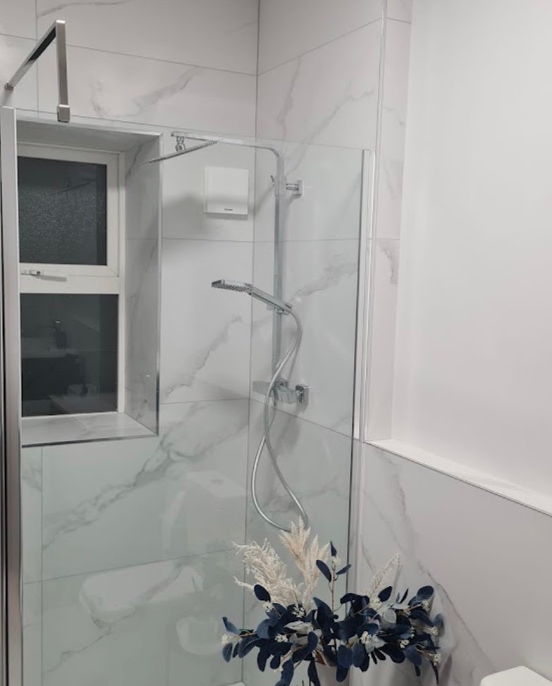 White marble bathroom with glass walk-in shower panel